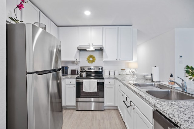 kitchen featuring white cabinets, light stone countertops, light wood-type flooring, sink, and stainless steel appliances