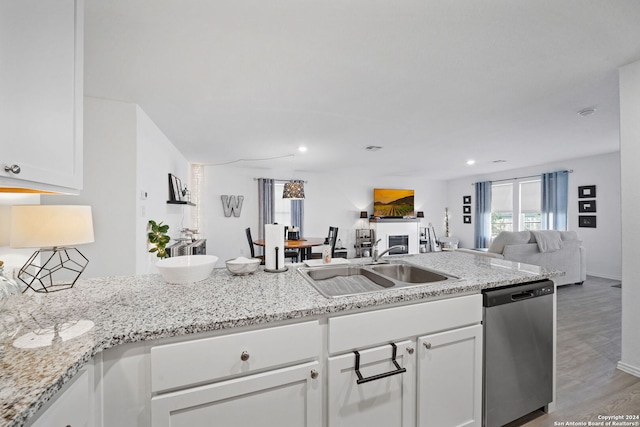 kitchen featuring sink, hardwood / wood-style floors, stainless steel dishwasher, white cabinets, and light stone counters