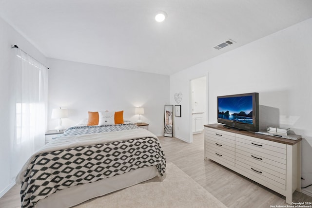 bedroom with ensuite bathroom and light hardwood / wood-style flooring