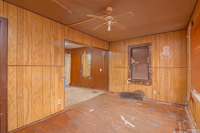 unfurnished room featuring ceiling fan and wood walls