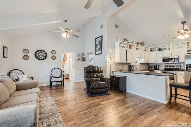 living room with hardwood / wood-style floors, ceiling fan, high vaulted ceiling, beamed ceiling, and sink