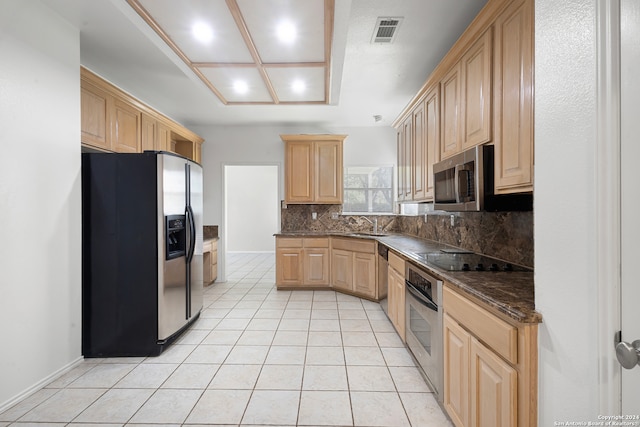 kitchen with stainless steel appliances, backsplash, dark stone counters, light tile patterned floors, and light brown cabinetry