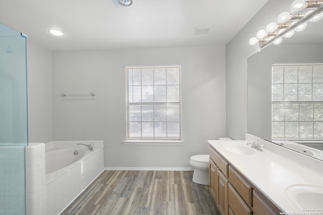 bathroom featuring a healthy amount of sunlight, toilet, a relaxing tiled tub, and wood-type flooring