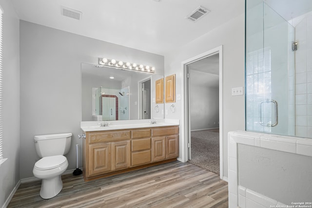 bathroom featuring vanity, an enclosed shower, hardwood / wood-style floors, and toilet