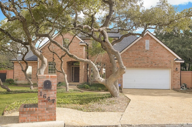 traditional-style home featuring concrete driveway, brick siding, a garage, and a shingled roof