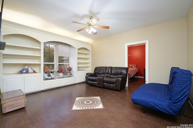 living room with built in shelves, ceiling fan, and dark wood-type flooring