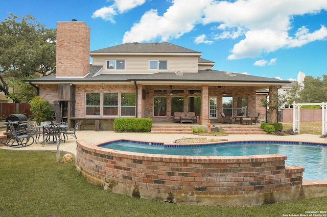 rear view of property featuring a yard, a patio, ceiling fan, and a pool with hot tub