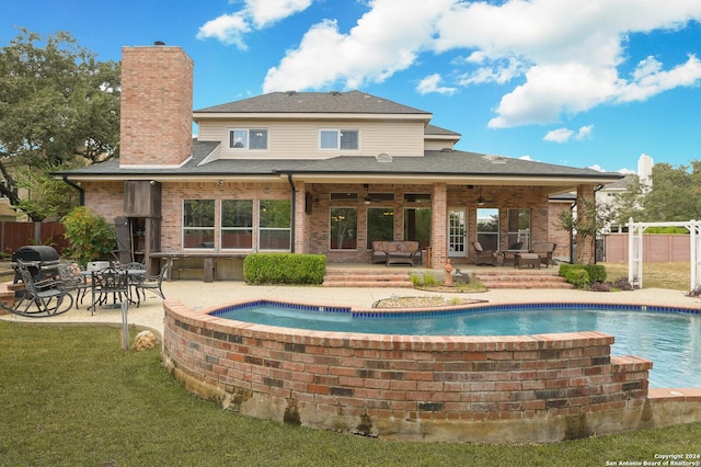 back of property with a patio, an outdoor pool, brick siding, and a chimney