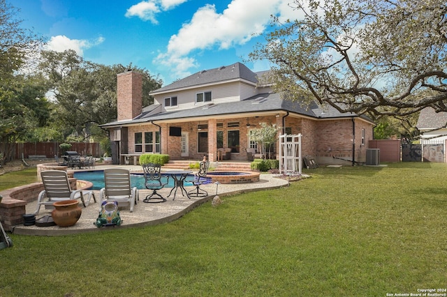 back of house with an in-ground hot tub, a patio area, a chimney, brick siding, and roof with shingles