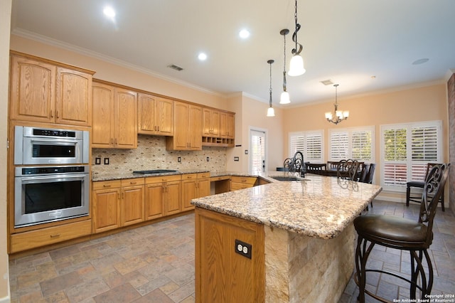 kitchen with a sink, stone tile flooring, a kitchen breakfast bar, a chandelier, and light stone countertops