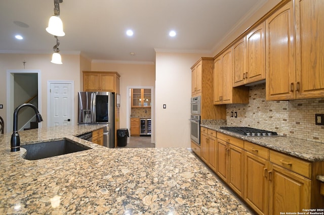 kitchen with a sink, appliances with stainless steel finishes, light stone counters, decorative backsplash, and ornamental molding