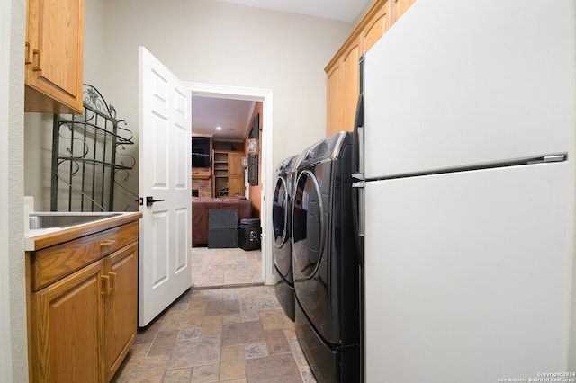 clothes washing area with washer and dryer, cabinets, and sink