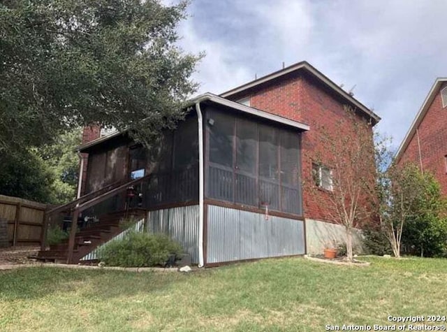 view of side of property featuring a lawn and a sunroom