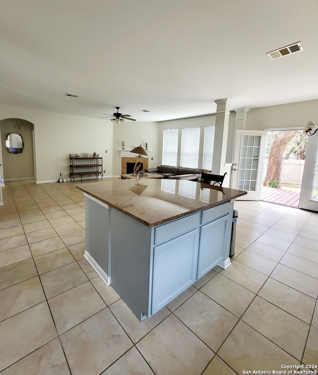 kitchen featuring light tile patterned flooring, a center island, white cabinetry, and light stone counters