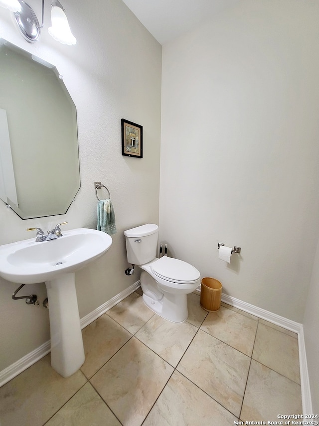 bathroom with toilet, tile patterned floors, and sink