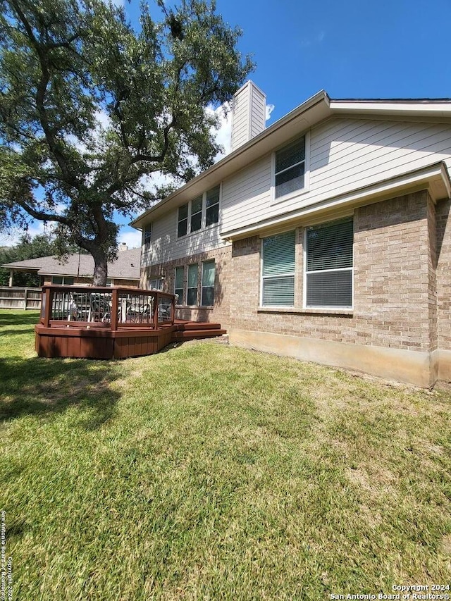 back of house with a wooden deck and a lawn