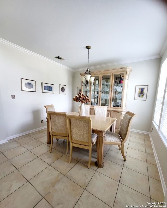 tiled dining area featuring ornamental molding and an inviting chandelier