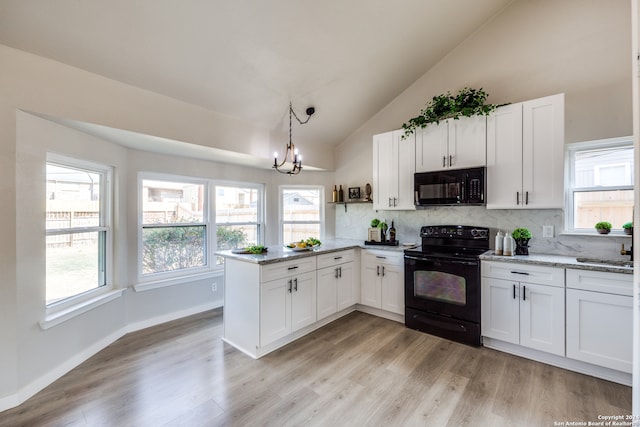 kitchen with vaulted ceiling, white cabinets, and black appliances