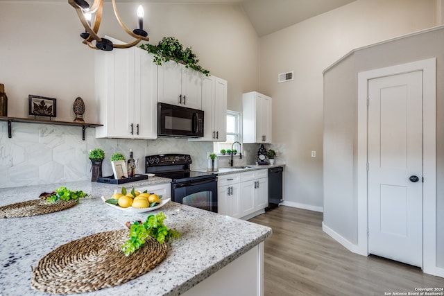 kitchen featuring sink, white cabinetry, tasteful backsplash, light stone countertops, and black appliances