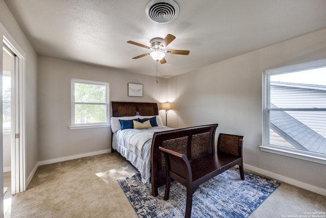 bedroom featuring multiple windows, light carpet, and ceiling fan