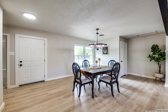 dining space featuring a textured ceiling, light hardwood / wood-style flooring, and a chandelier