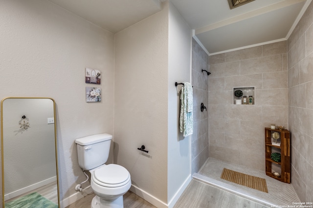 bathroom featuring tiled shower, wood-type flooring, and toilet