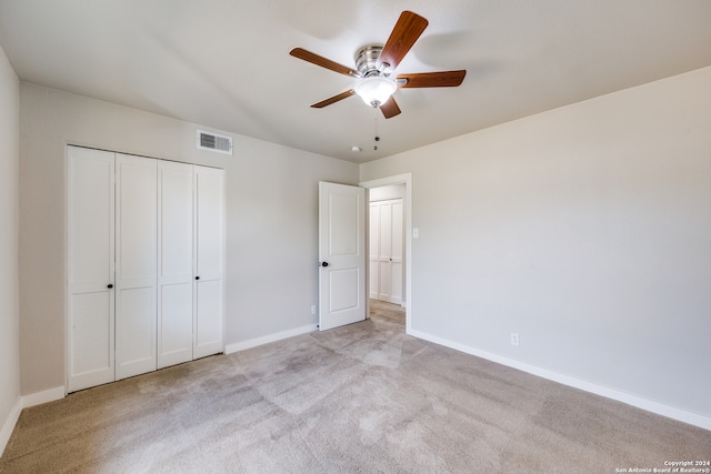 unfurnished bedroom featuring ceiling fan, a closet, and light carpet