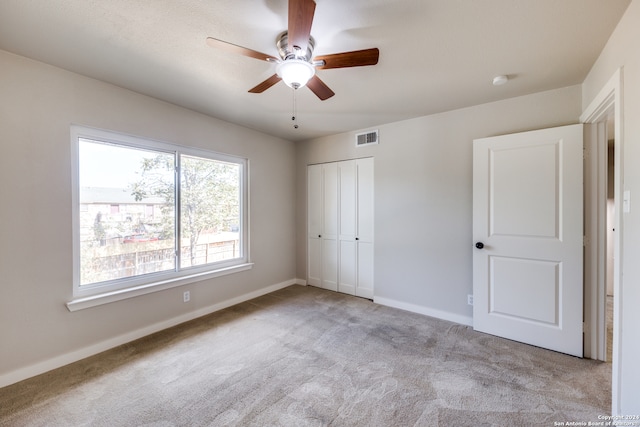 unfurnished bedroom featuring light carpet, ceiling fan, and a closet