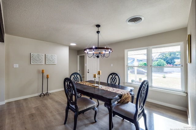 dining room featuring a wealth of natural light, a textured ceiling, a chandelier, and light hardwood / wood-style flooring