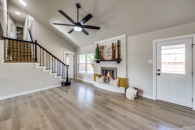 unfurnished living room featuring vaulted ceiling, ceiling fan, a fireplace, and light hardwood / wood-style floors