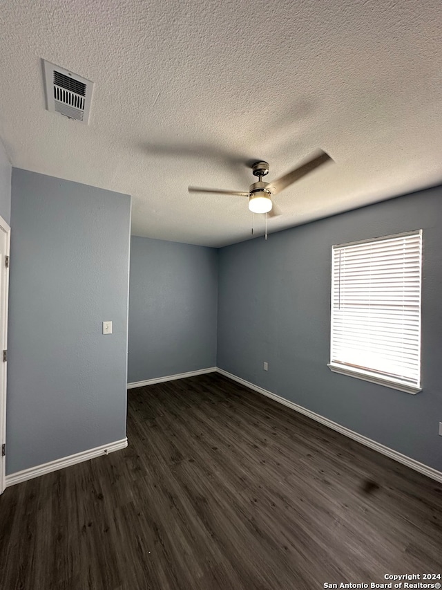 empty room featuring dark wood-type flooring, a textured ceiling, and ceiling fan