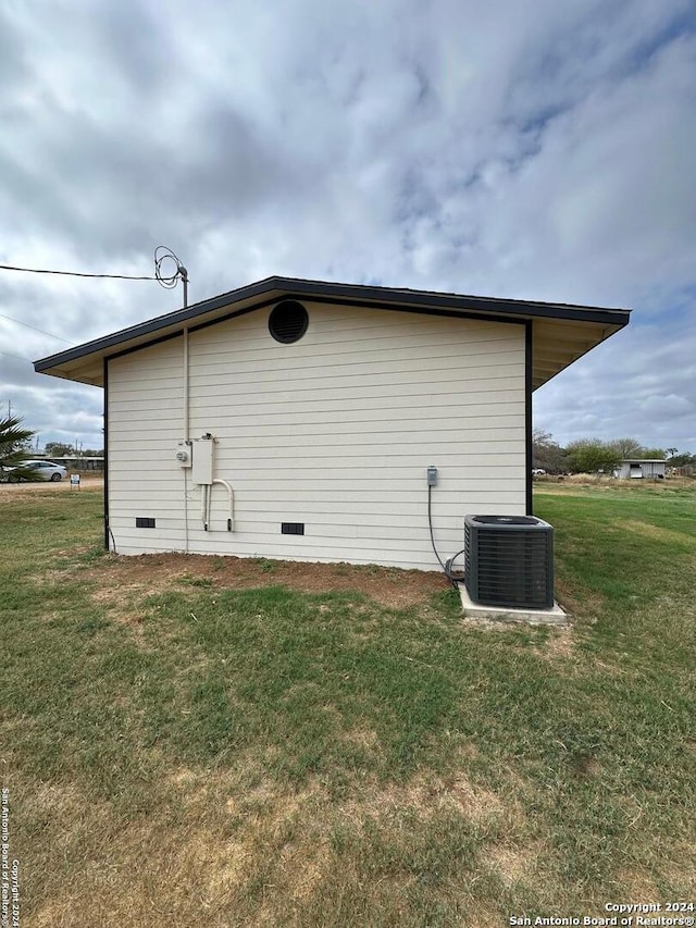 view of side of home with a yard and central AC unit