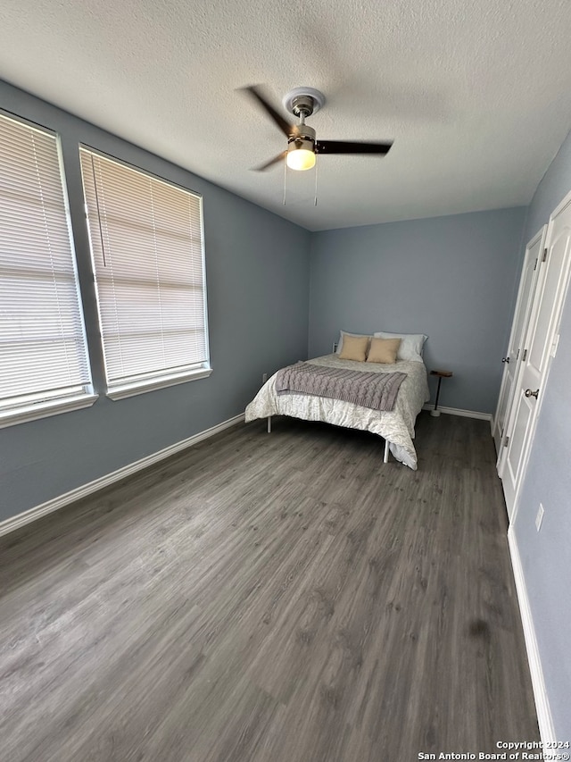 bedroom featuring multiple windows, ceiling fan, and dark hardwood / wood-style flooring