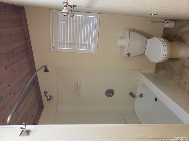 bathroom featuring a bathing tub, a textured ceiling, and toilet