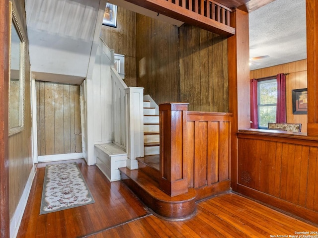 stairs featuring ceiling fan, wood walls, and hardwood / wood-style floors