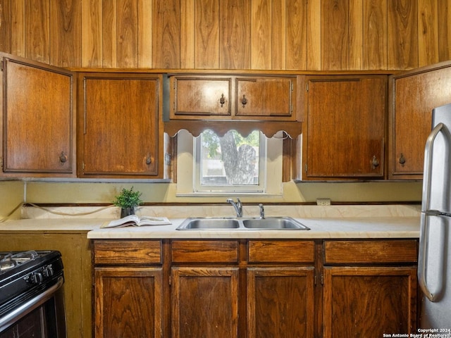 kitchen with black stove, sink, and white fridge