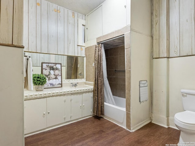 full bathroom featuring hardwood / wood-style flooring, toilet, shower / bath combo with shower curtain, vanity, and a textured ceiling