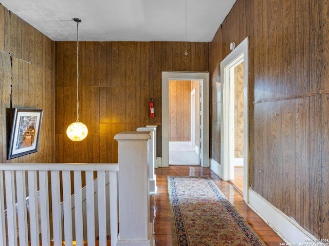 hallway with hardwood / wood-style flooring and wooden walls