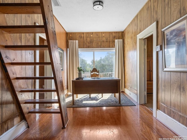 unfurnished office with a textured ceiling, hardwood / wood-style flooring, and wooden walls