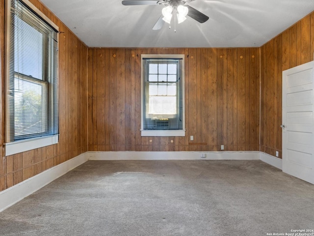 carpeted empty room with wooden walls and ceiling fan