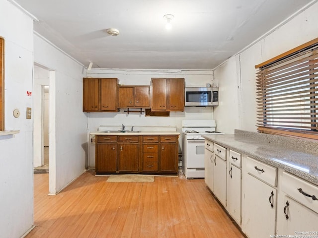 kitchen featuring sink, light hardwood / wood-style floors, white cabinetry, and white gas stove