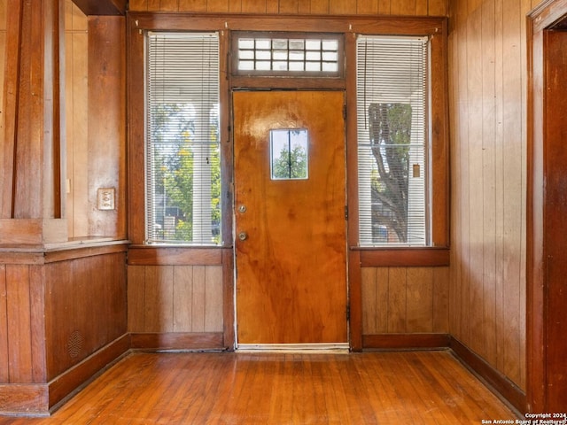 doorway with hardwood / wood-style floors and wooden walls