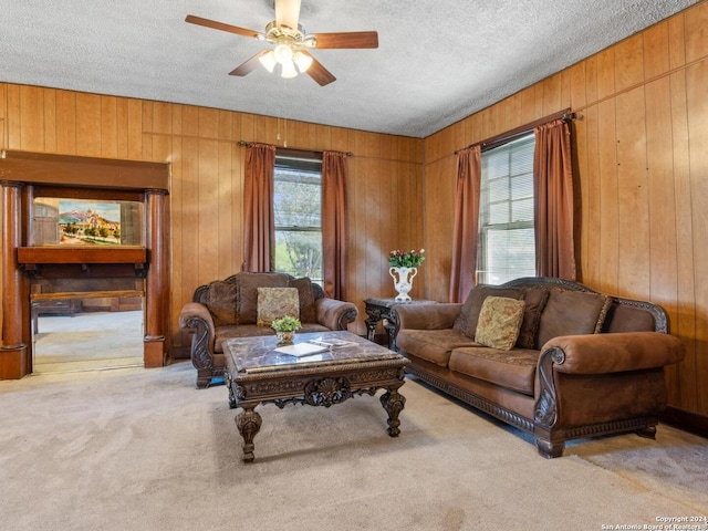 carpeted living room featuring ceiling fan, a textured ceiling, and wood walls