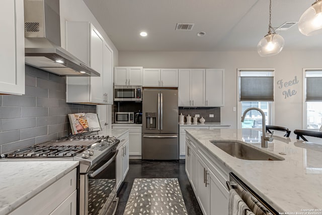 kitchen with wall chimney exhaust hood, stainless steel appliances, backsplash, sink, and light stone counters