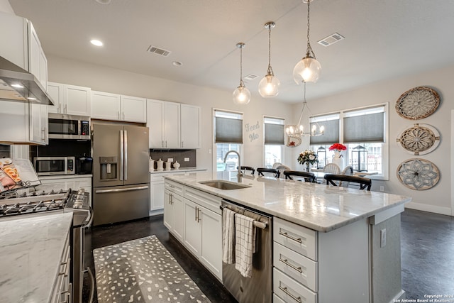 kitchen with decorative backsplash, a kitchen island with sink, sink, light stone countertops, and appliances with stainless steel finishes