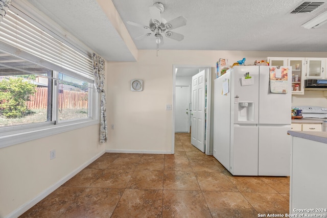 kitchen featuring range hood, white cabinets, a textured ceiling, and white appliances