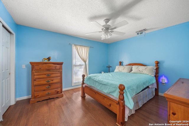 bedroom with a textured ceiling, dark hardwood / wood-style floors, a closet, and ceiling fan