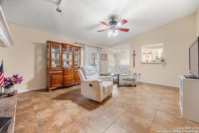 sitting room with vaulted ceiling, a textured ceiling, light tile patterned floors, and ceiling fan