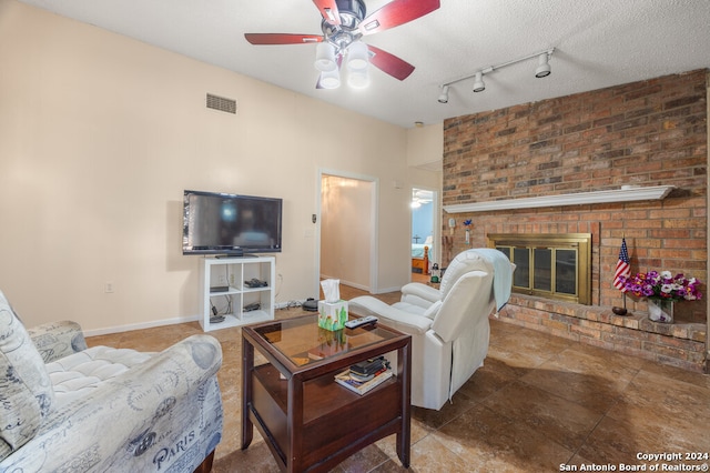 living room with a textured ceiling, ceiling fan, and a brick fireplace