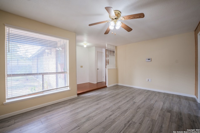 spare room with a textured ceiling, light wood-type flooring, and ceiling fan